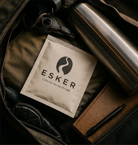 An Esker Coffee pouch packed inside a travel bag beside a flask and notebook